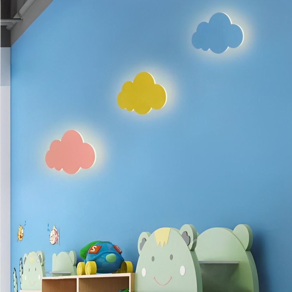 Es gibt drei Wandleuchten in Form einer Wolke: eine blaue, eine rosa und eine gelbe, die an einer blauen Wand in einem Kinderzimmer hängen