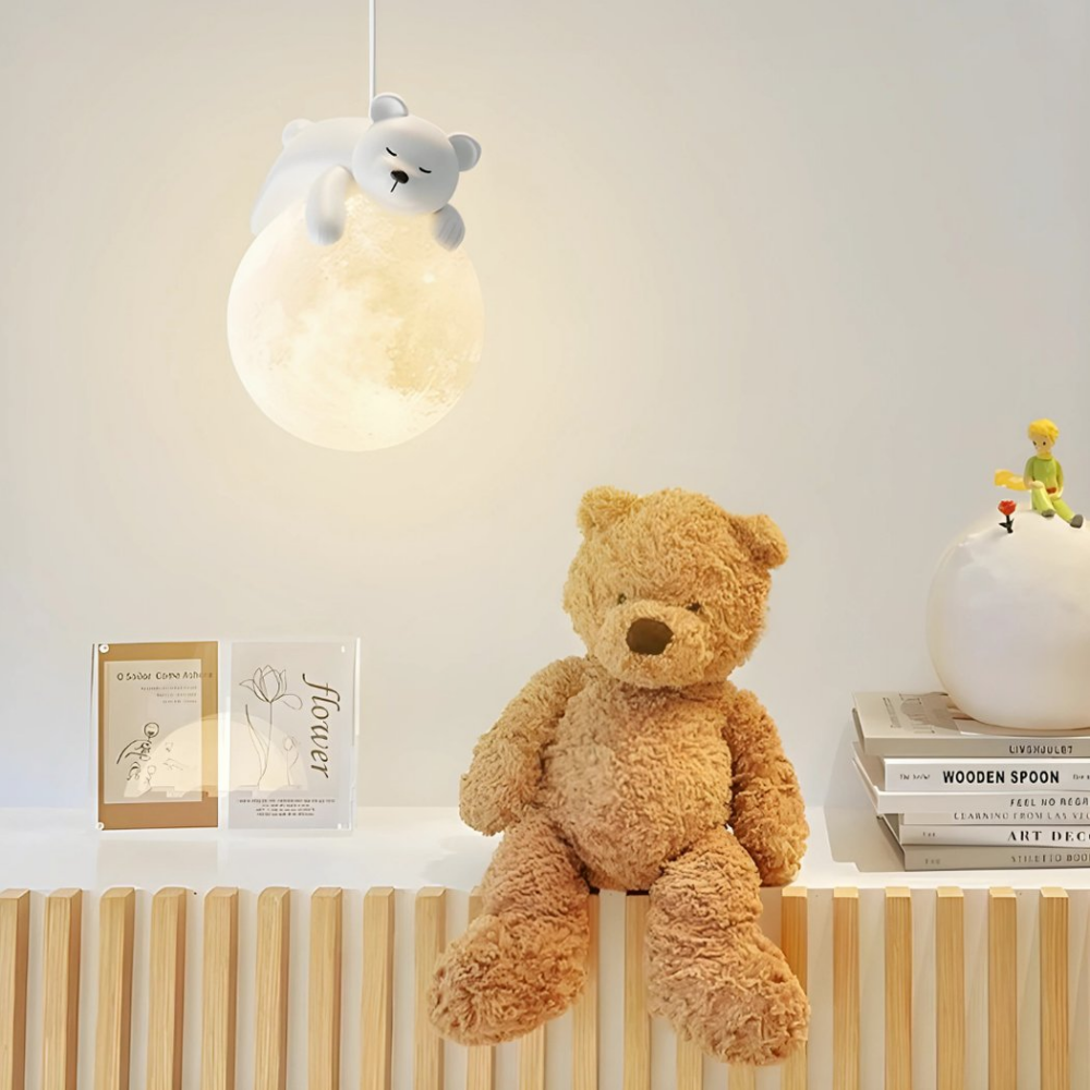 Wandleuchte mit schlafendem Bären auf dem Mond hängt in einem Babyzimmer und neben einem großen Teddybären