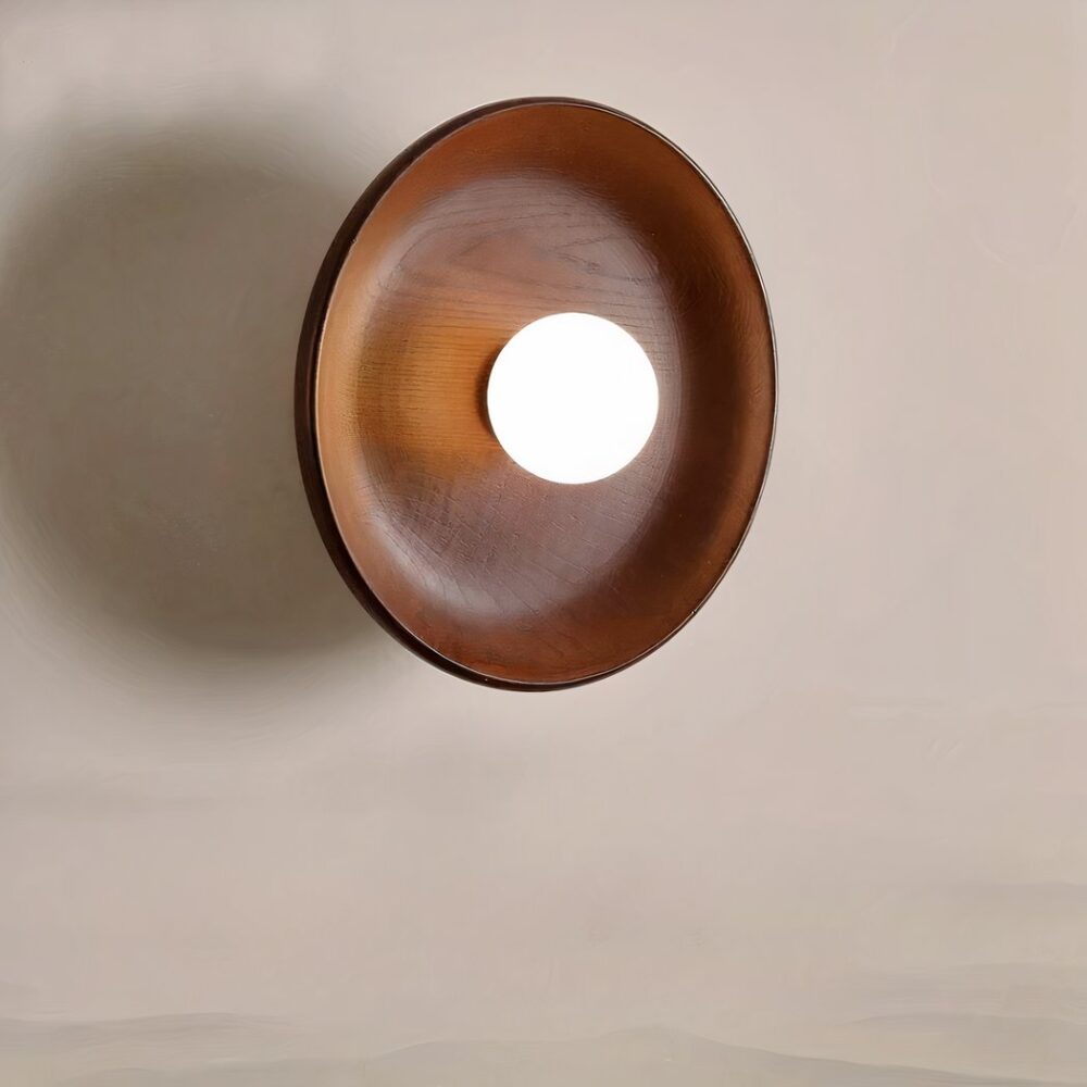 Runde Wandleuchte aus Holz mit Walnuss-Finish an einer beigen Wand und eingeschaltet.