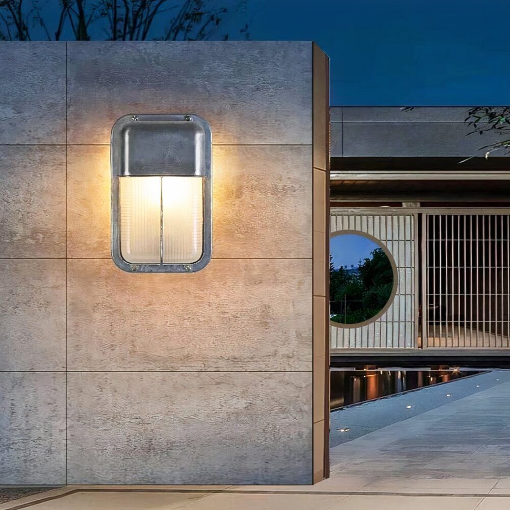 an einer Außenwand ist eine rechteckige, graue Wandleuchte im Industriestil für innen und außen zu sehen