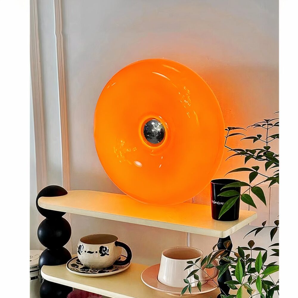 man sieht eine runde Wandleuchte aus orangefarbenem Glas an einer Wohnzimmerwand