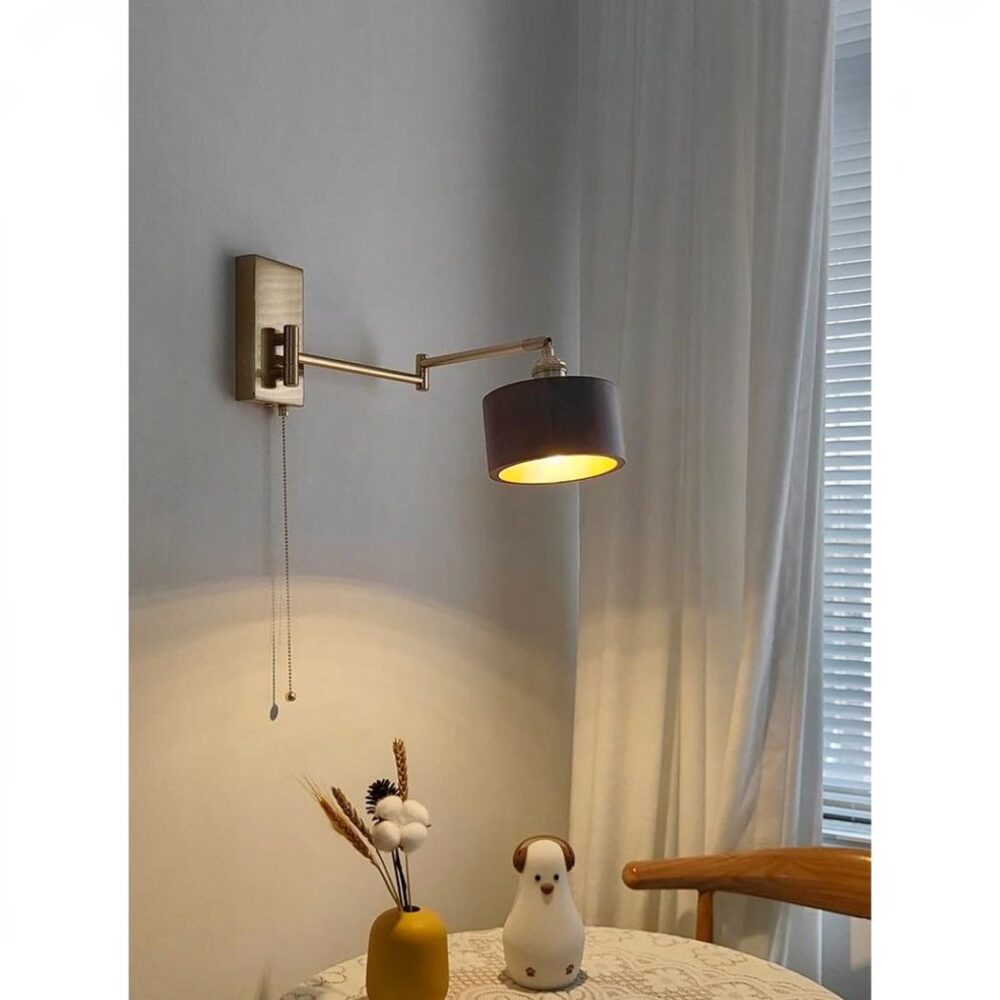 man sieht in einem weißen Wohnzimmer eine Wandleuchte aus dunklem Holz und Messingbeschlägen, die an einer Wand über einem Tisch mit weißer Tischdecke angebracht ist