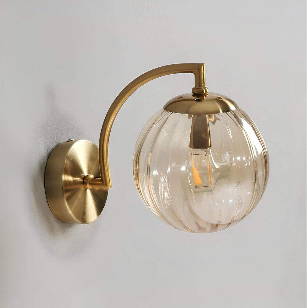 Wandleuchte im Vintage-Stil mit goldener Struktur und Rauchglaskugel mit vertikalen Rillen. Die Wandleuchte ist an einer grauen Wand angebracht.