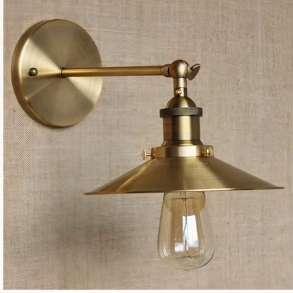 man sieht an einer hellbraunen Wand eine goldene Wandleuchte im Industriestil mit flachem Schirm