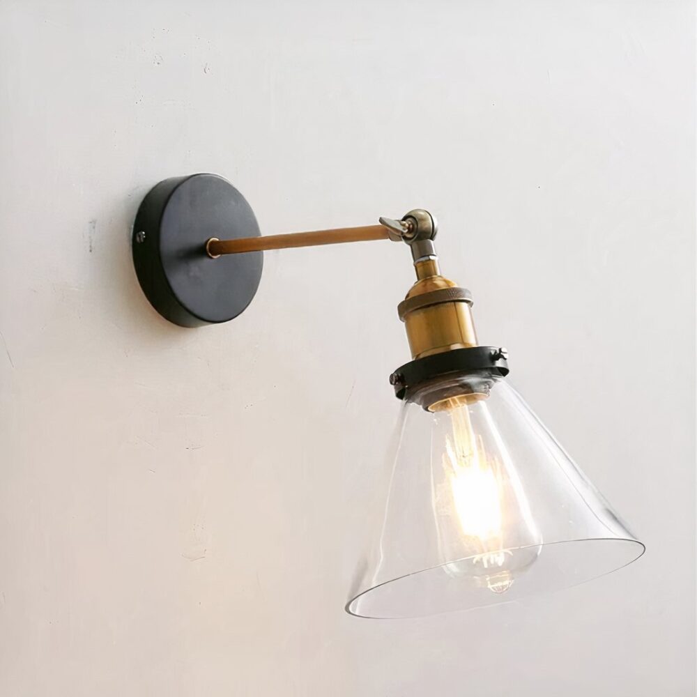 man sieht an einer hellgrauen Wand eine Wandleuchte mit transparentem Glasschirm im Industriestil angeschraubt