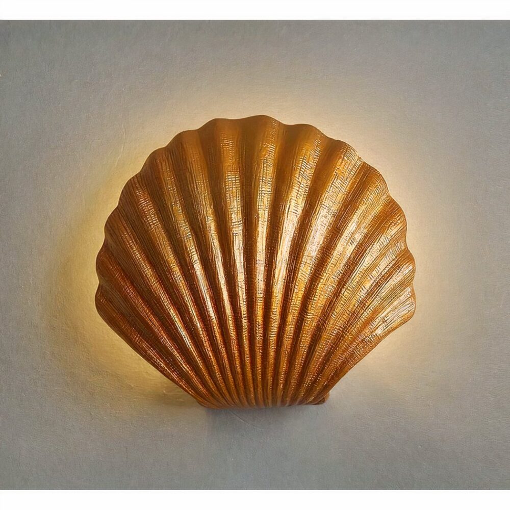 sieht man an einer hellgrauen Wand eine Wandleuchte in Form einer goldenen Muschel