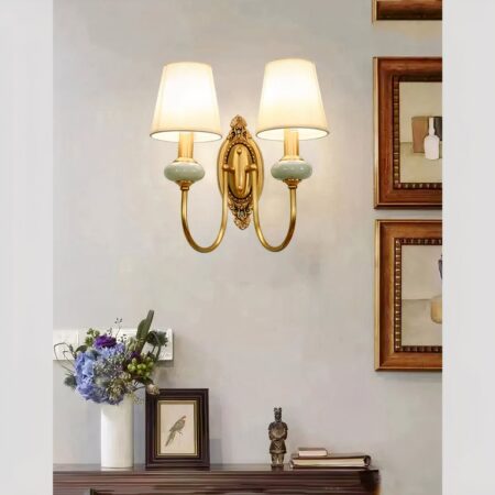 Vintage-Wandleuchte aus Keramik und Stoffschirm, die eingeschaltet und an der Wand eines Wohnzimmers über eine Kommode befestigt ist.