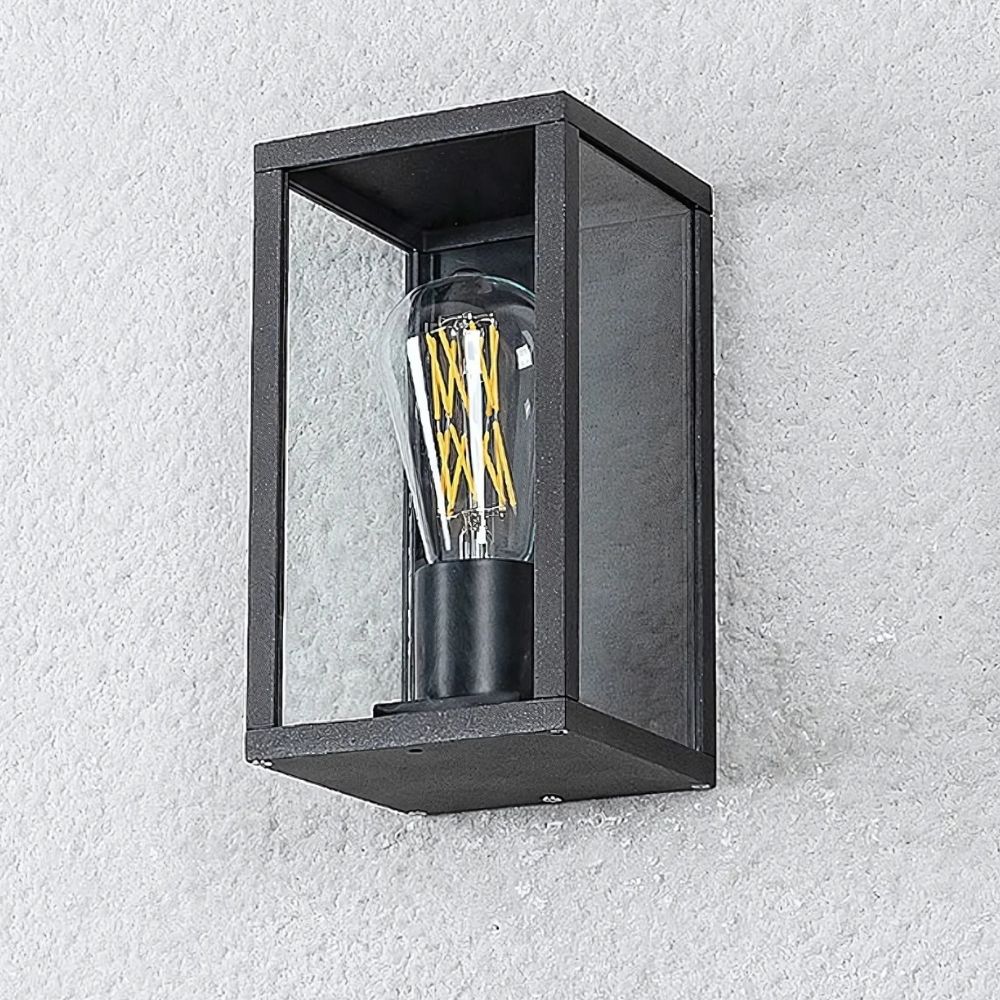 Wandleuchte für den Außenbereich mit sichtbarer Glühbirne in Form eines Kastens mit schwarzen Metallkonturen, bei dem die ausgeschaltete Glühbirne sichtbar ist. Wird an einer weißen Außenwand befestigt.